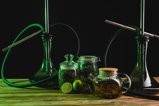 Dry tea, teapot and hookahs on wooden surface isolated on black  - Фото, зображення