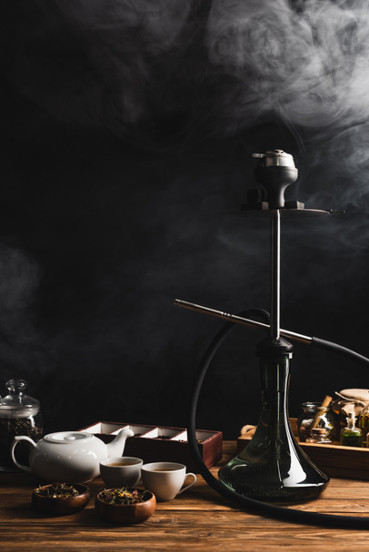 Hookah, té y tetera sobre fondo negro con humo - Foto, Imagen