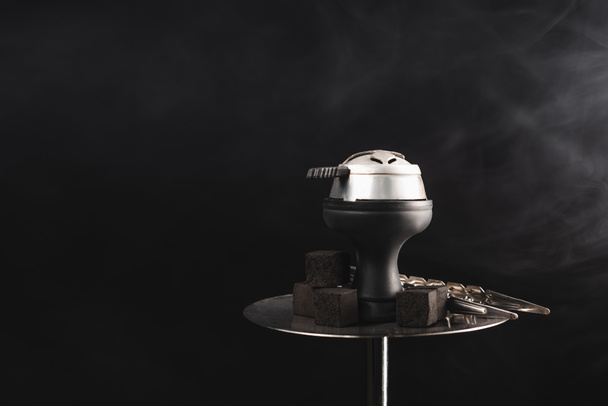 Coals and tweezers on hookah on black background with smoke  - Foto, Imagem