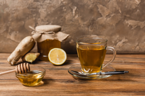 Tea and honey in bowl on wooden surface on textured stone background  - Φωτογραφία, εικόνα