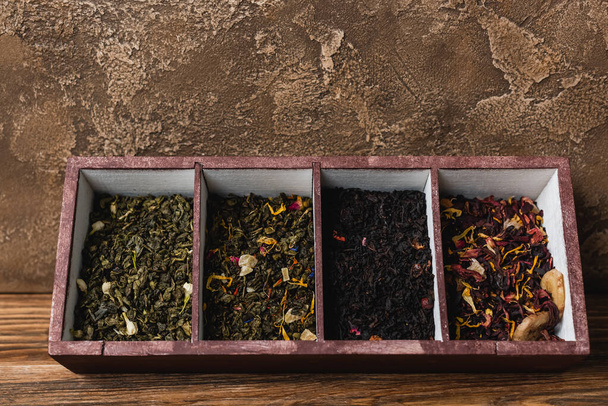 Top view of dry tea in box on wooden surface on textured stone background  - 写真・画像