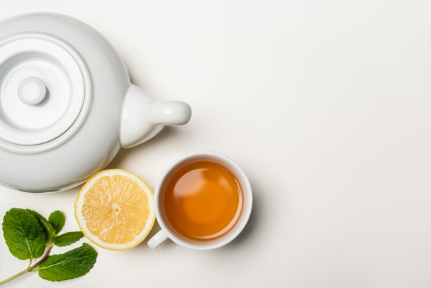 Top view of cup of tea, lemon and mint on white background with copy space - Foto, afbeelding