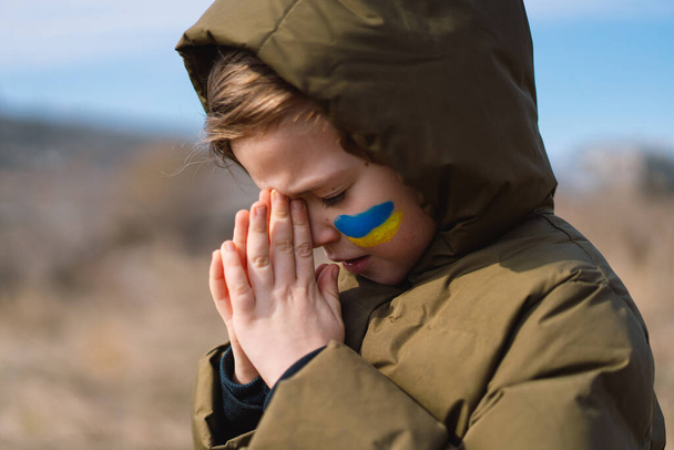 menino ucraniano fechou os olhos e orando para parar a guerra na Ucrânia. - Foto, Imagem