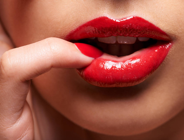 El deseo viene en rojo. Foto recortada de una mujer presionando su dedo contra su labio. - Foto, imagen