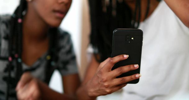 Two black girls looking at cellphone screen laughing together. African American ethnicity - Foto, Imagem
