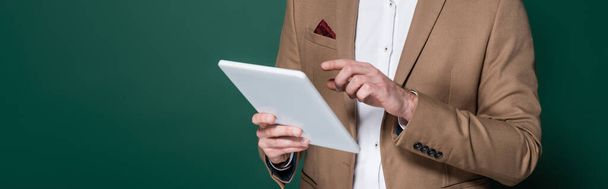 oříznutý pohled na mladého muže pomocí digitálního tabletu na tmavě zelené, banner - Fotografie, Obrázek