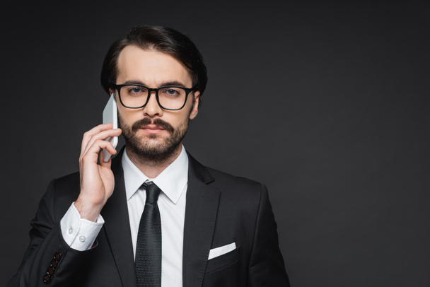 businessman with mustache talking on smartphone on dark grey - Foto, immagini