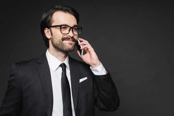happy businessman with mustache talking on smartphone on dark grey - Zdjęcie, obraz
