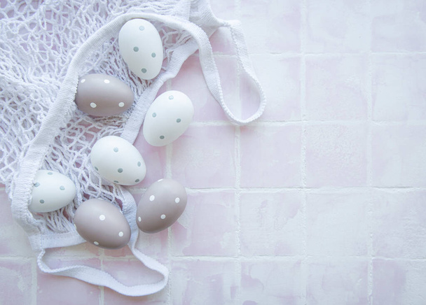 String bag with Easter eggs and spring blossom on pink tile background - Foto, Imagen