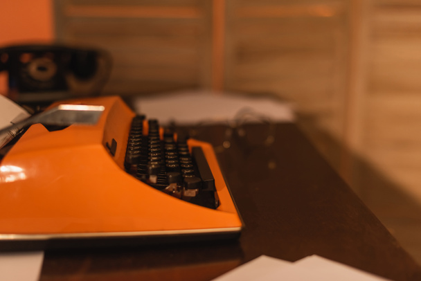máquina de escribir antigua y naranja cerca de papeles en el escritorio - Foto, Imagen