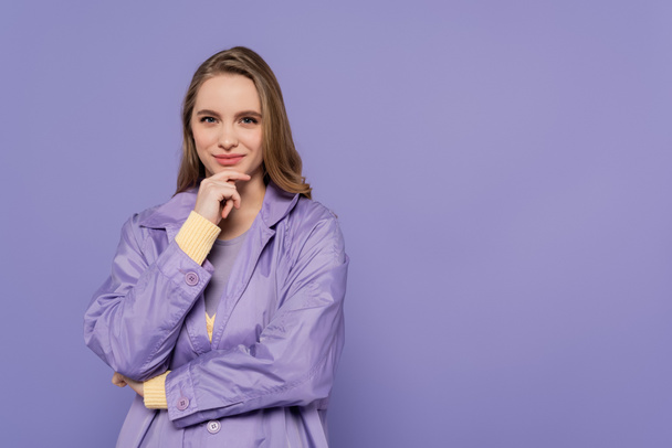 pleased young woman in trench coat isolated on purple - Photo, Image