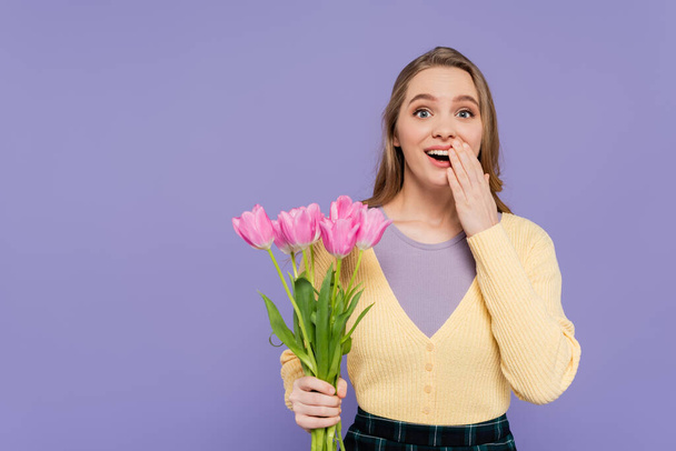 excited young woman holding pink tulips isolated on purple - Fotografie, Obrázek