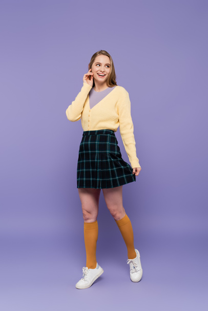 full length of young woman in skirt smiling on purple - Foto, afbeelding