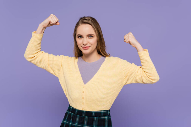 щаслива молода жінка демонструє силовий жест ізольовано на фіолетовому
 - Фото, зображення