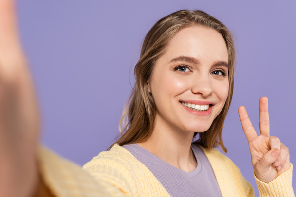 cheerful young woman showing peace sign isolated on purple - Φωτογραφία, εικόνα