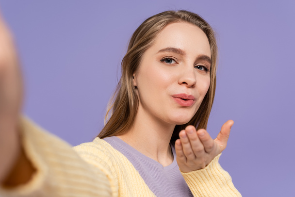mladá žena posílání vzduchu polibek izolované na fialové - Fotografie, Obrázek