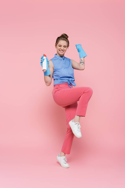 幸せな若い女性の完全な長さでゴム手袋保持空気清浄機ボトルオンピンク  - 写真・画像