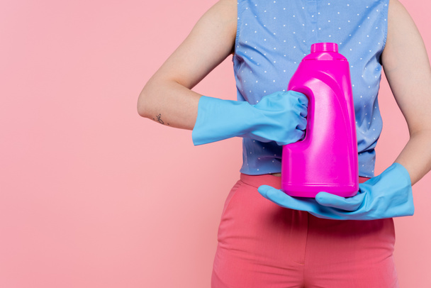 cropped view of tattooed woman in rubber gloves holding bright bottle with detergent isolated on pink  - Fotografie, Obrázek