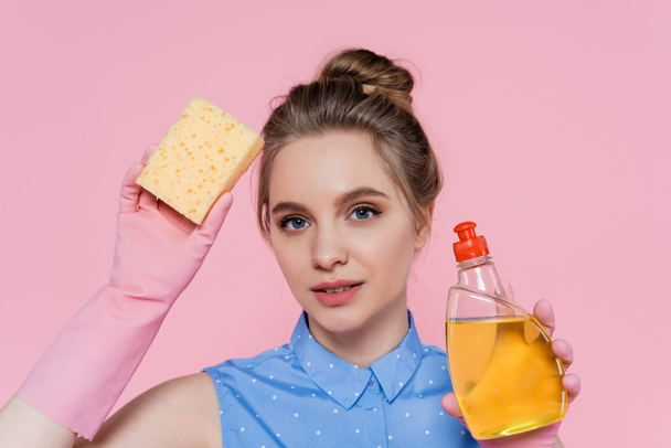 young woman holding sponge and bottle with detergent isolated on pink  - Fotoğraf, Görsel