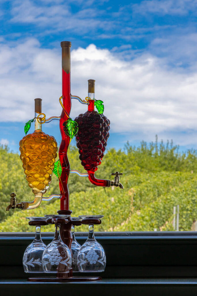 glas karaf met witte en rode wijn in de vorm van een druif en wijngaard achtergrond - Foto, afbeelding