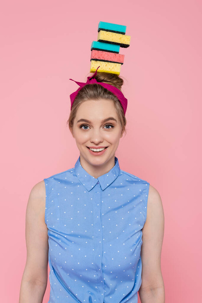 happy young woman with stacked sponges on head isolated on pink  - Fotó, kép