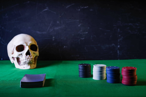 Kártyázunk és zsetonozunk. Pókerasztal és koponya. Veszélyes szerencsejáték. Játék a halállal. Pókerasztal és koponya. Előnézet. - Fotó, kép