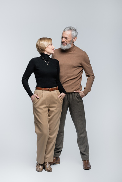 Trendy mature man looking at blonde wife on grey background  - Fotografie, Obrázek