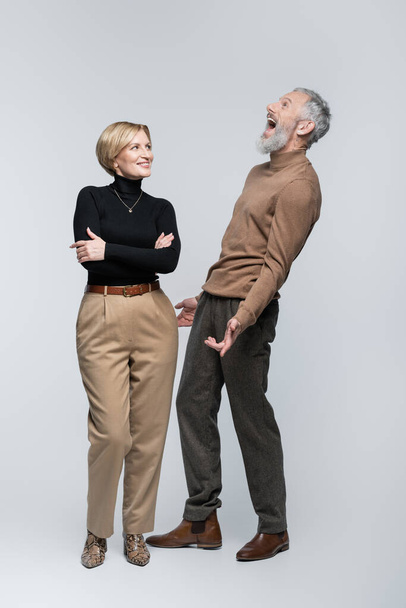 Excited mature man standing near stylish wife on grey background  - Фото, зображення