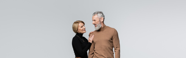 Usmívající se dospělá žena dotýkající se vousatého manžela izolované na šedé, prapor  - Fotografie, Obrázek