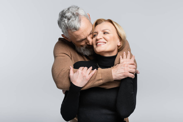Grey haired man kissing and hugging wife isolated on grey  - Φωτογραφία, εικόνα