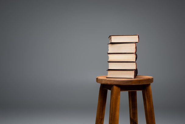 Taburete de madera con pila de libros aislados en gris - Foto, Imagen