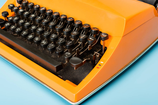 στενή άποψη του μαύρου πληκτρολογίου της γραφομηχανής πορτοκαλί στο μπλε - Φωτογραφία, εικόνα