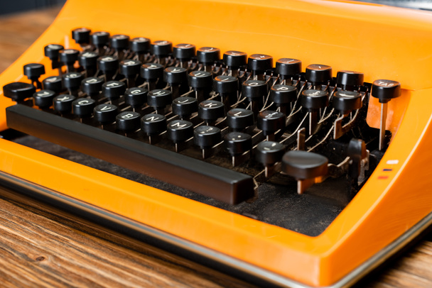 vue rapprochée de la machine à écrire orange avec clavier noir sur bureau en bois - Photo, image