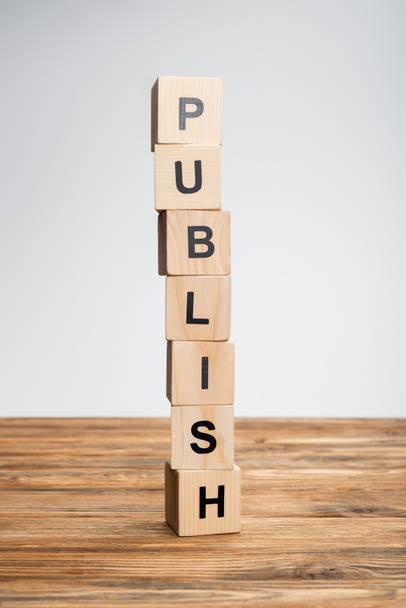 stack of cubes with publish lettering on wooden surface isolated on grey - Photo, Image