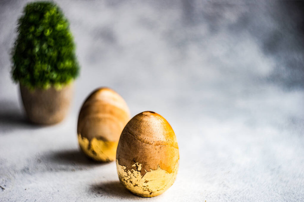 Concepto tarjeta de Pascua con huevos de madera y plantas verdes en maceta - Foto, Imagen