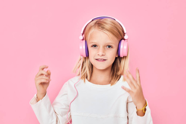 menina bonito com cabelo loiro usando fones de ouvido fundo rosa - Foto, Imagem