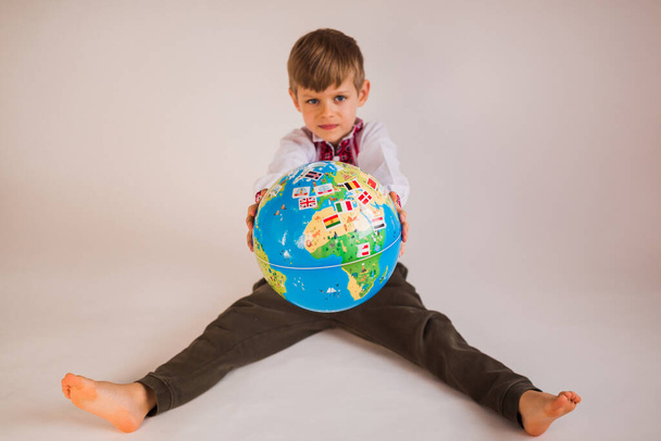 boy in ukrainian t-shirt holding globe in hands - isolated on wh - Photo, image