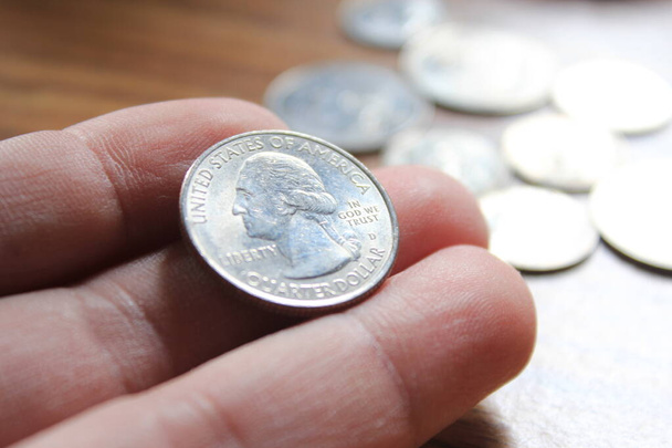 ręka podnoszenia monety ćwierć monety w amerykańskiej walucie rozłożone na drewnianej podłodze - Zdjęcie, obraz