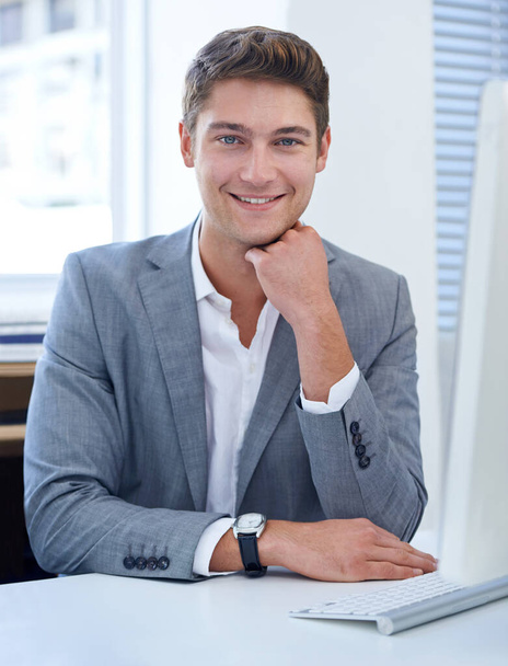 Enjoying his job to the fullest. A satisfied young businessman sitting at his desk. - Foto, Bild