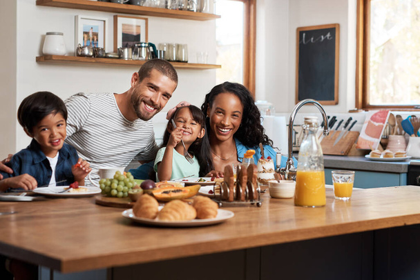 Breakfast will put you in a great mood. Shot of a family of four enjoying breakfast together at home. - Photo, image