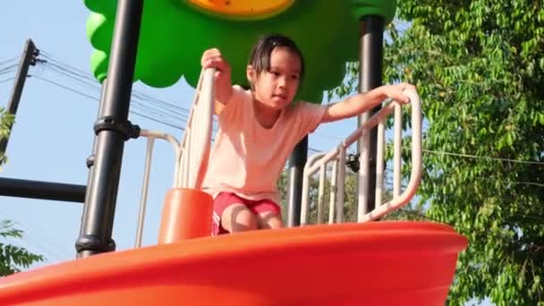 Actief meisje op de speelplaats buiten. Schattig klein meisje glijdt naar beneden op slider. Gezonde zomeractiviteit voor kinderen. - Video