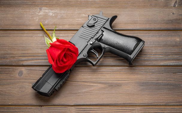 Rose petals and pistol on board. Peace concept. - Photo, Image
