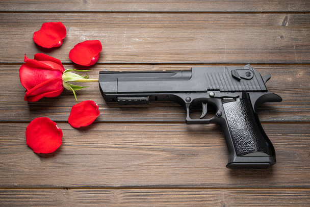 Rose petals and pistol on board. Peace concept. - Photo, Image