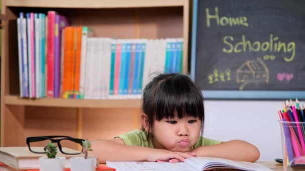 Aziatisch schoolmeisje dat zich verveelt tijdens het studeren thuis tijdens quarantaine. Nieuw Normaal. Thuisonderwijs. - Video