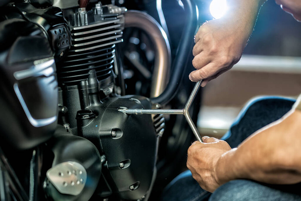 Mecánico usando una llave y un zócalo en el motor de una motocicleta en el garaje .maintenance, concepto de la motocicleta de la reparación .selective foco - Foto, imagen