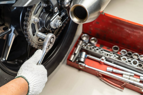 Motosiklet kazığında anahtar ve soket kullanan tamirci. Motosiklet garajında bakım ve onarım konsepti. Seçici odaklanma  - Fotoğraf, Görsel