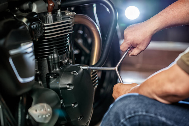 mechanic repairing motorcycle using wrench or socket on the engine of  motorcycle , maintenance,repair motorcycle concept in garage - Foto, imagen