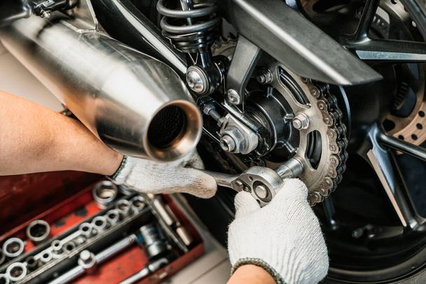 Motosiklet kazığında anahtar ve soket kullanan tamirci. Motosiklet garajında bakım ve onarım konsepti. Seçici odaklanma  - Fotoğraf, Görsel