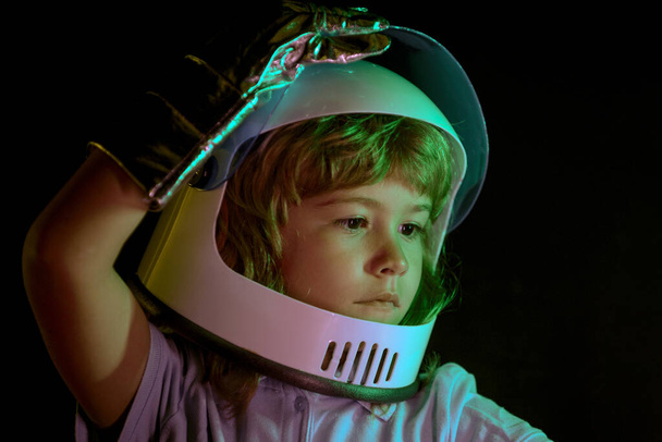 Child boy imagines himself to be an astronaut in an space helmet. Close up kids portrait isolated on black, adventure imagination. - Foto, imagen