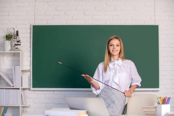 Young teacher with pointer. Beautiful student, cute blonde young woman in class at school. - Photo, Image